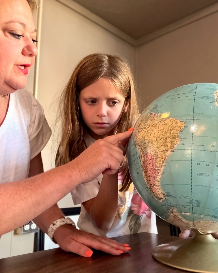 Lana Millard pointing out South America on a globe for a student